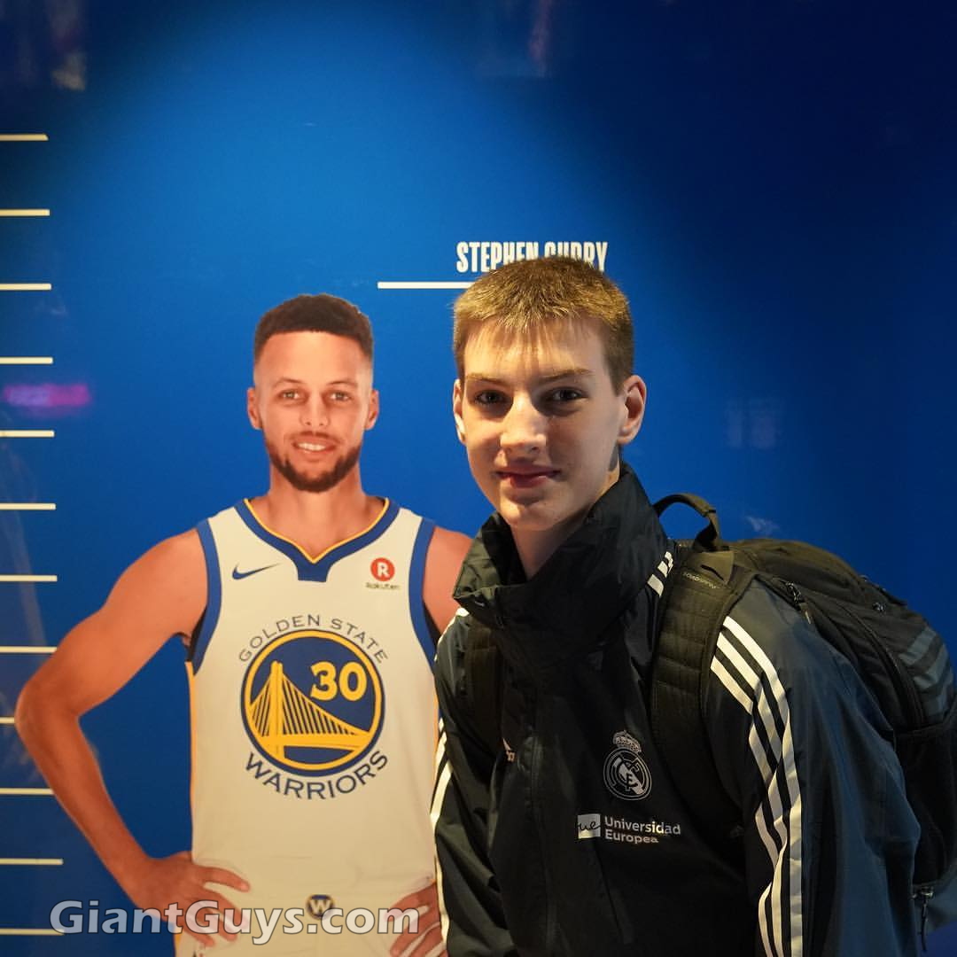 Olivier Rioux bending down next to 6ft3 NBA player Stephen Curry